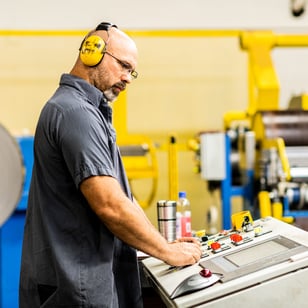Metal manufacturing employee standing at a machine