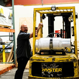 Smiling man standing with machine in warehouse