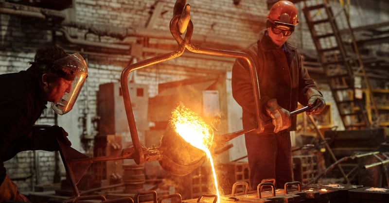 Man pouring melted metal in factory