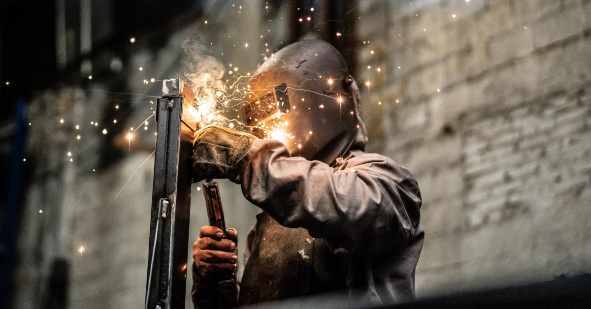 Person welding metal in a metal manufacturing warehouse