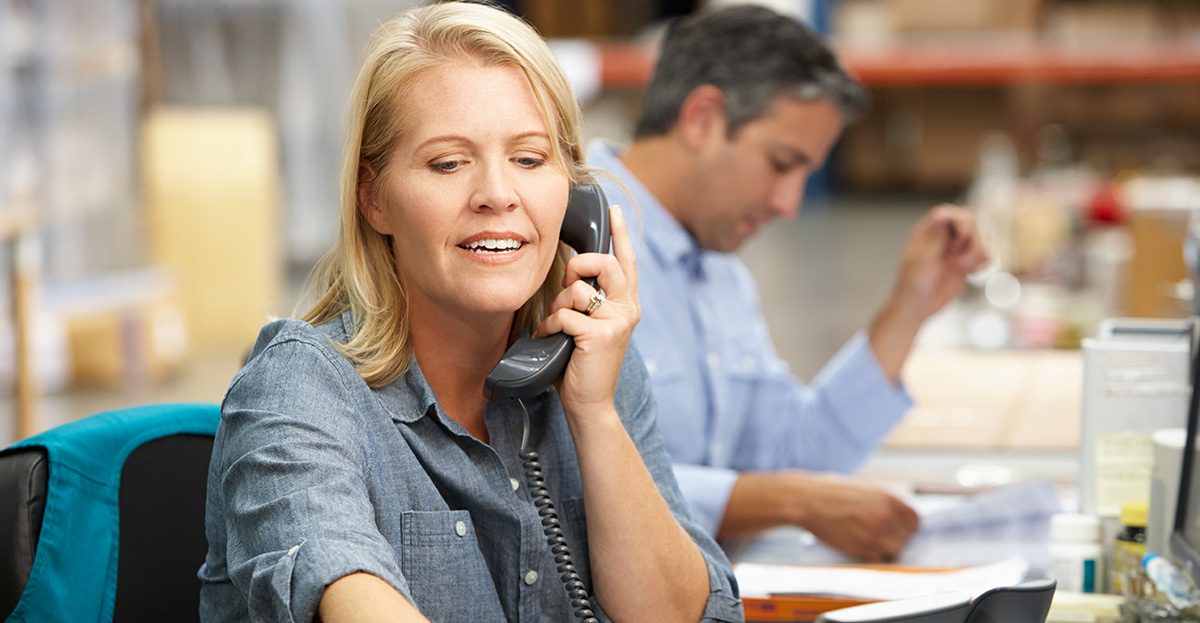 Woman answering phone at customer service metal shipping center