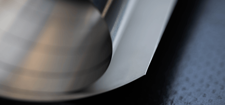 Image description: Rolled sheet of stainless steel across a dark background. 